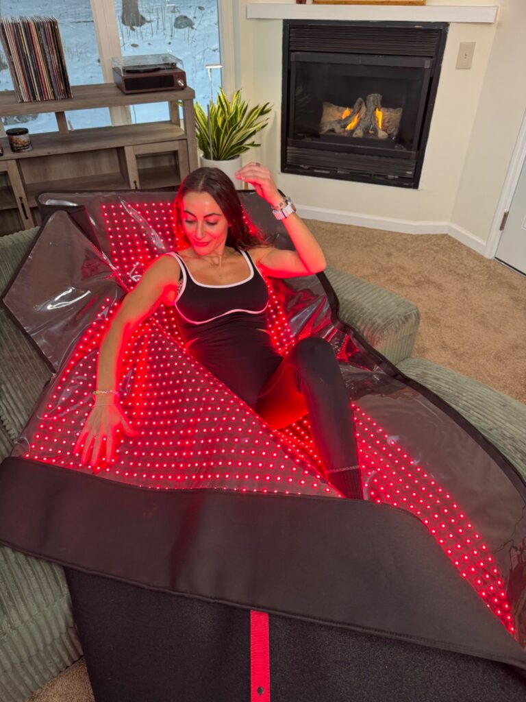 Woman relaxing on red light therapy mat at home — lifestyle shot